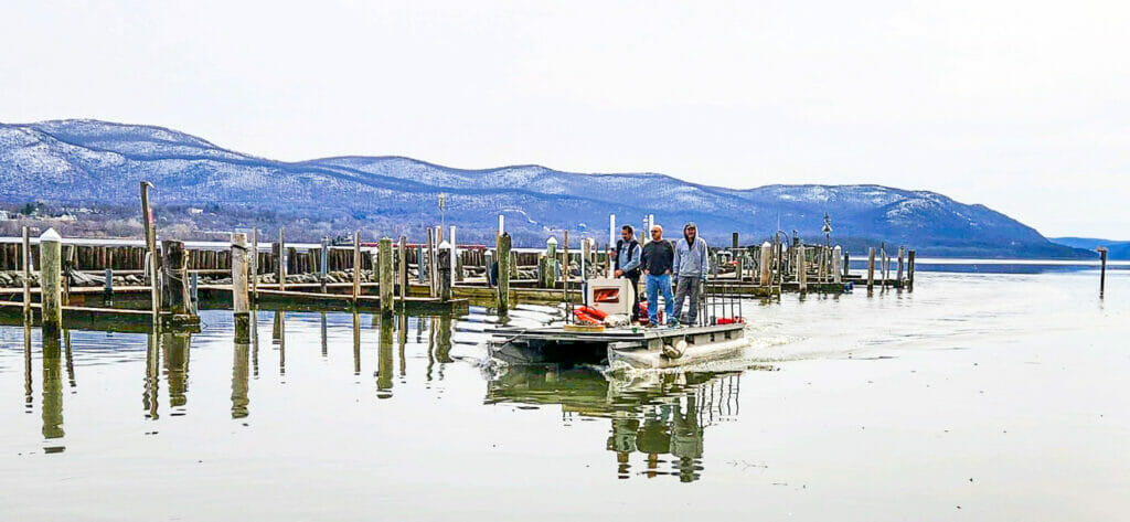 Club members enter the yacht club marina on the work boat.  The river and snow covered mountains in the background are very scenic,